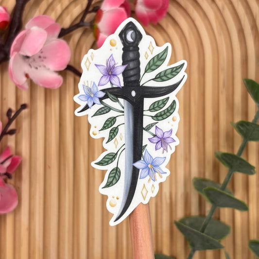 Close-up van sticker met bloemen rondom een fantasy dagger.