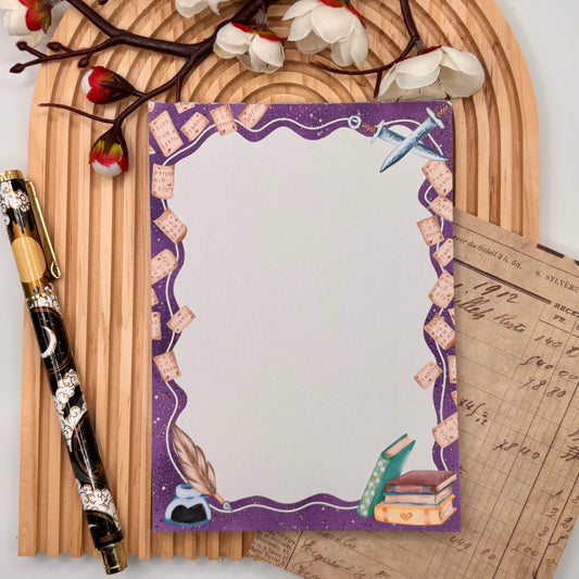 Fantasy notitieblok met paarse border, quill, inktpot, boeken en zwaarden – Arcane Tales design.