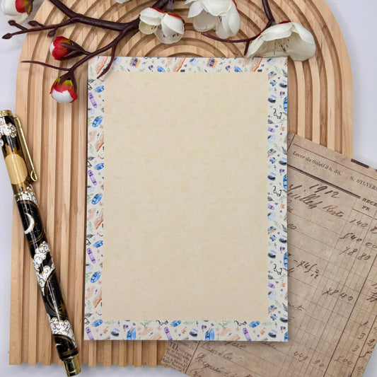 Notitieblok met boekenpatroon, quills, koffie en brilletjes – Book Nook design.