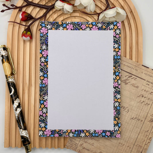 Notitieblok met bloemenrand op zwarte achtergrond – Midnight Blooms design.